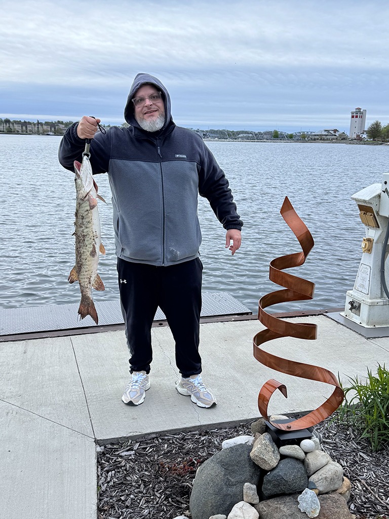 Fishing from the shore, Angel Ace Vasquez catches a tiger musky on the waterfront of Eagle View Suite.